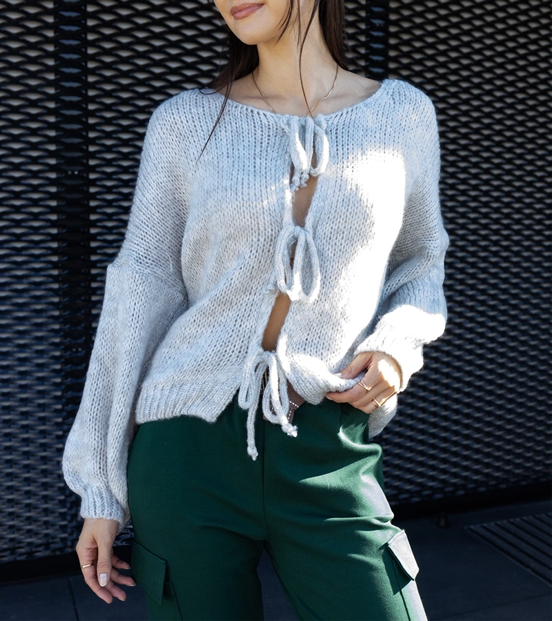 Szary wiązany sweterek Sumaia w języku rumuńskim to: **Pulover gri legat Sumaia**.